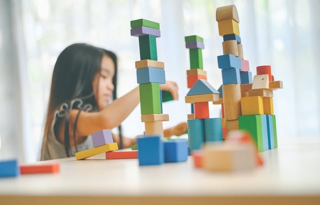 Une fille en train de jouer avec des cubes de construction colorés en bois
